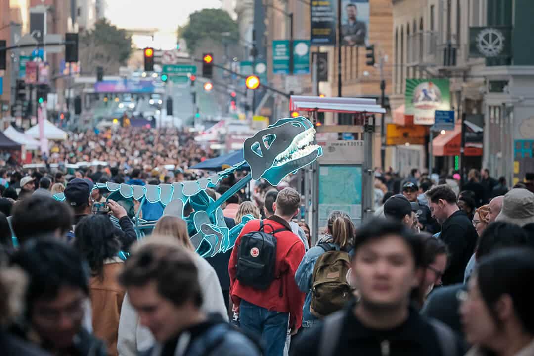 Large crowd at a busy downtown San Francisco street festival with a dinosaur installation
