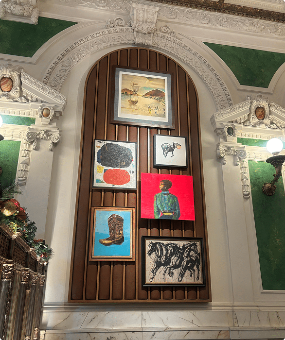 Framed artworks displayed on a wall inside an ornate historic interior
