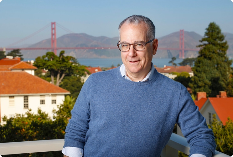 Man wearing glasses standing outdoors with the Golden Gate Bridge in the background