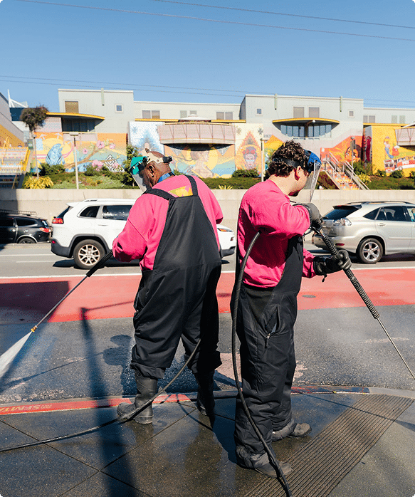 Two workers power washing a city sidewalk in San Francisco